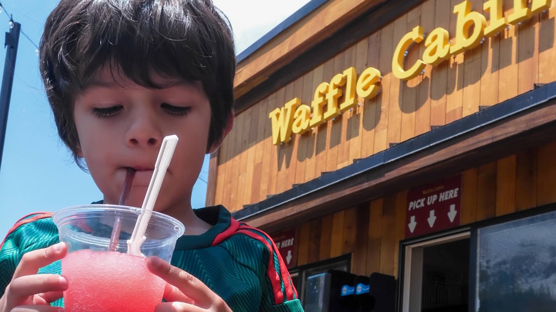 Kid sipping slushy from the Waffle Cabin during the summer