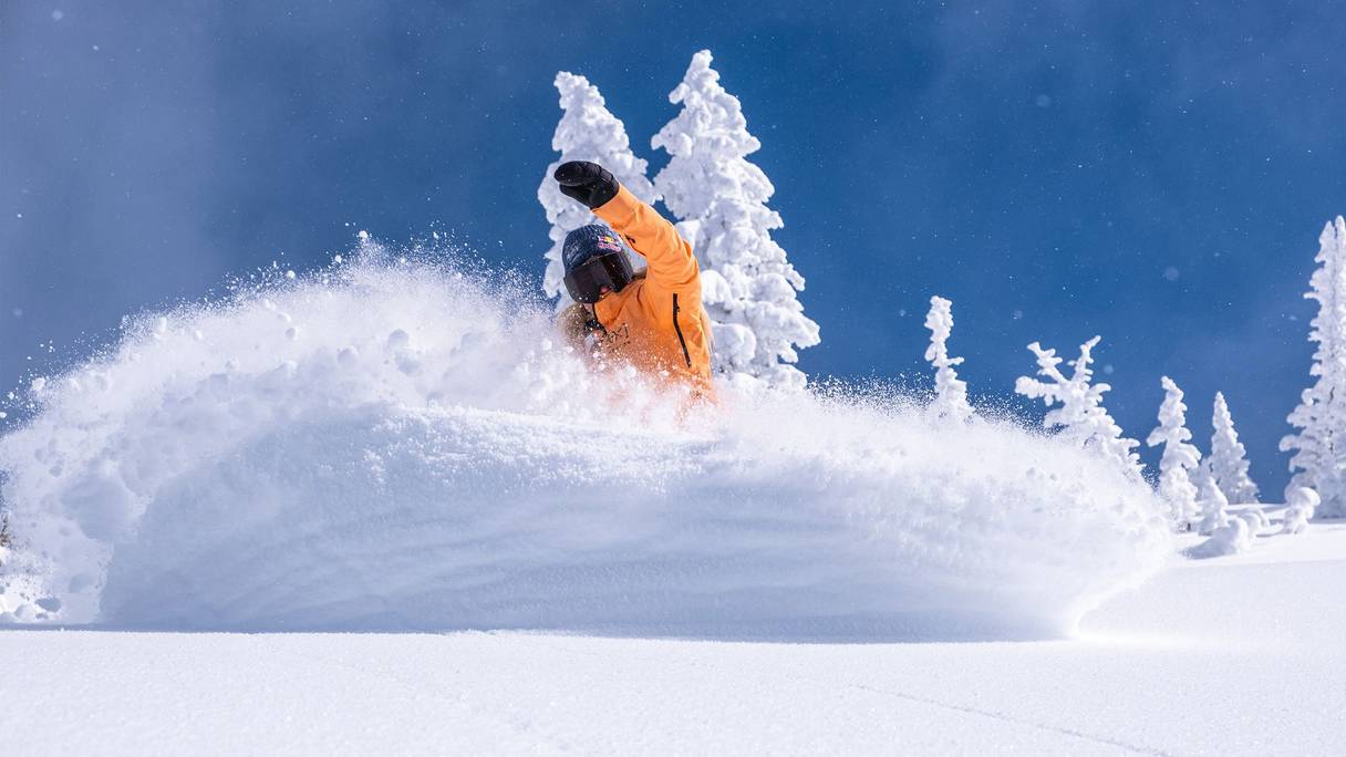 Snowboarder powder slash on a blue bird day