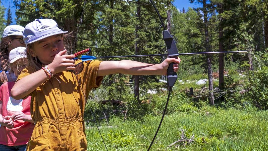 Kid with a bow and arrow in summer camp