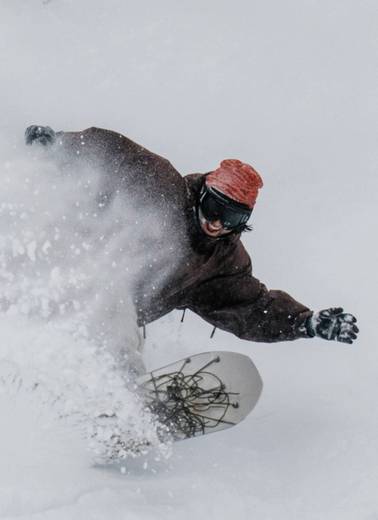 Snowboarder smiling while slashing deep powder at Brighton Ski Resort in Utah