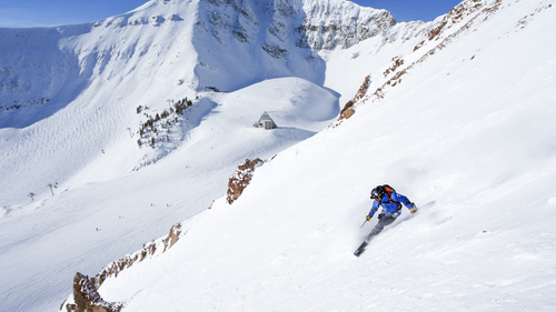 A person skiing down a steep trail in the winter.