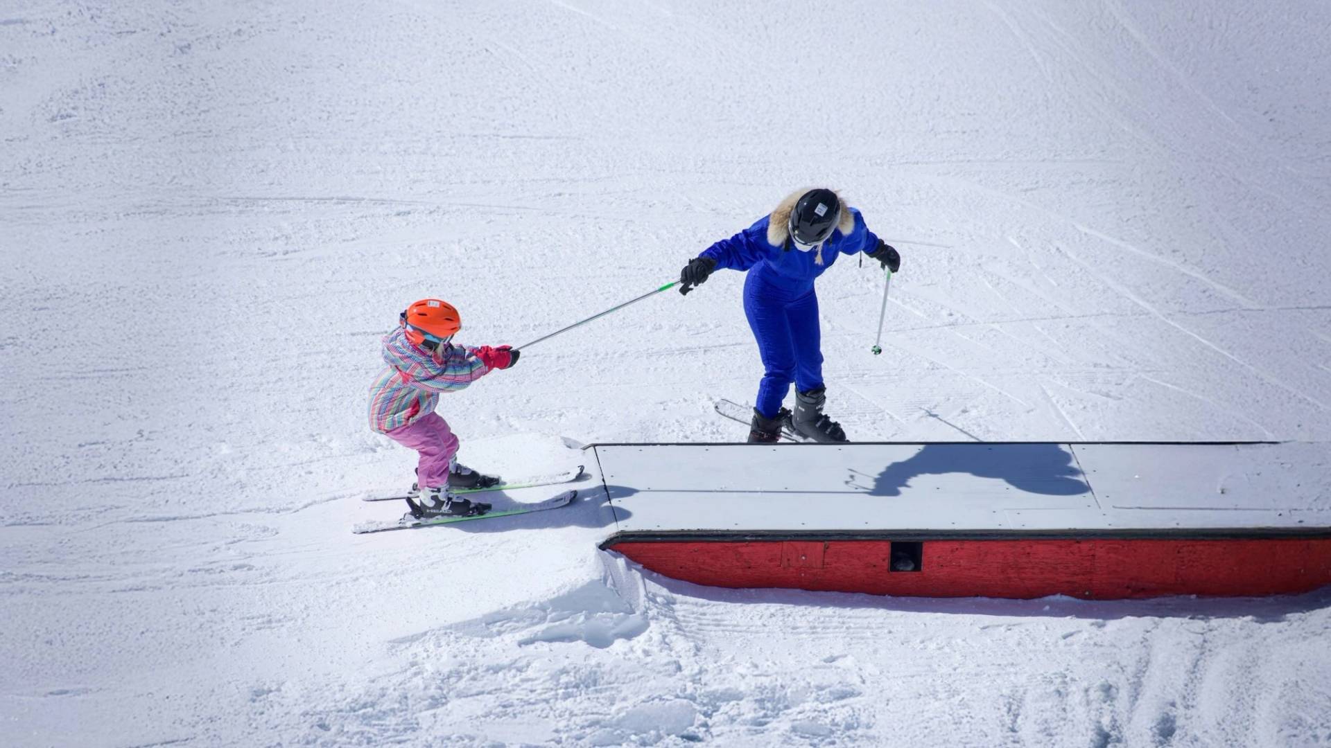 Kid skiing terrain park with mom at Brighton Resort