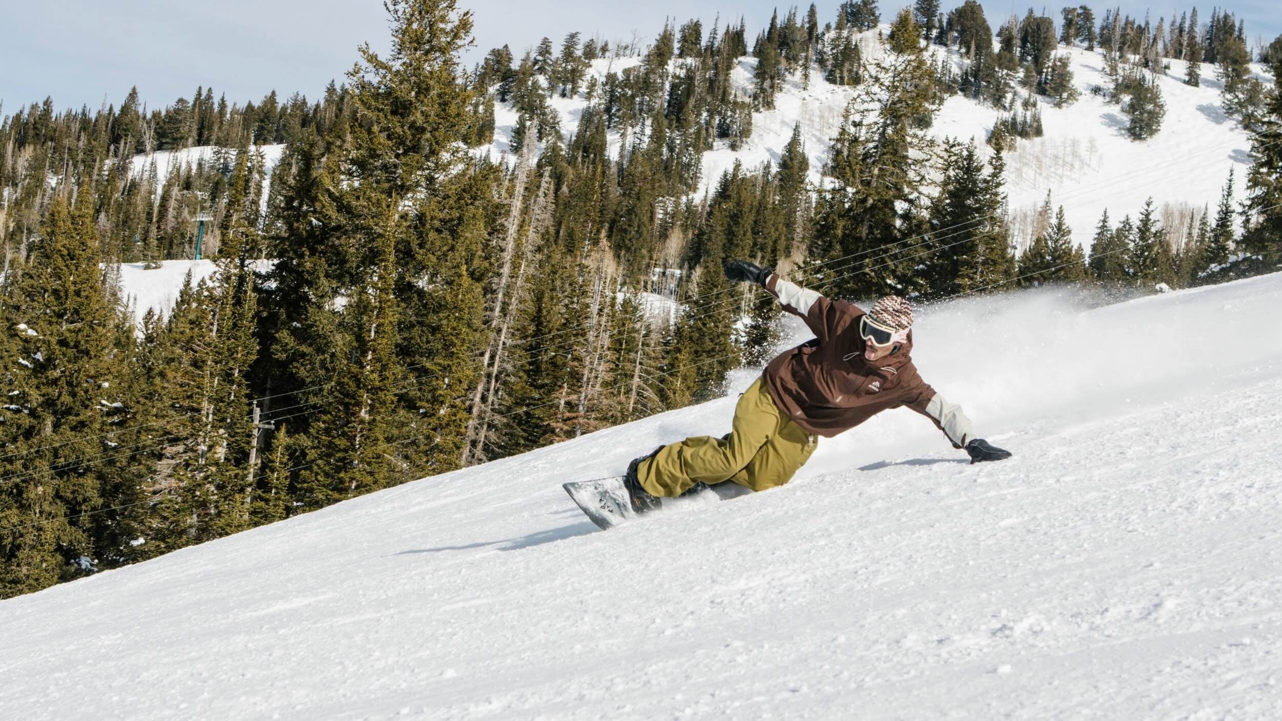 Snowboarder carving on a bluebird day at Brighton Resort in Utah