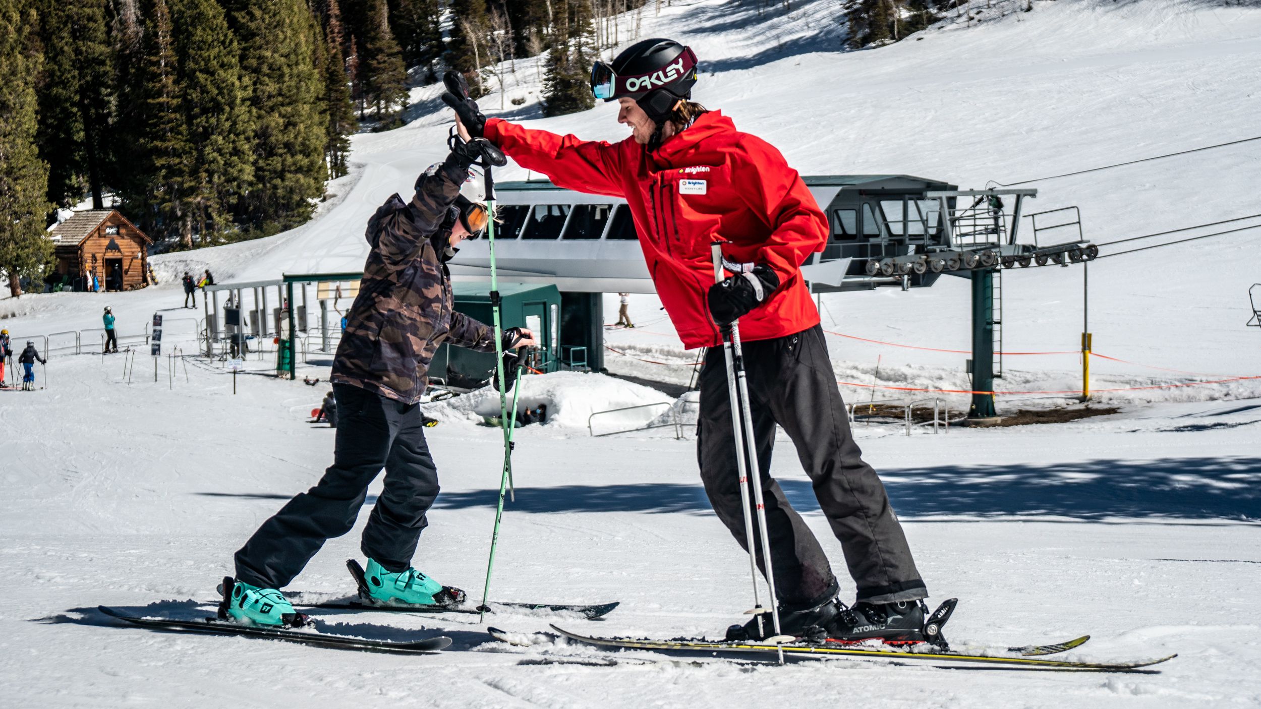 Kid high-fiving instructor during ski lesson