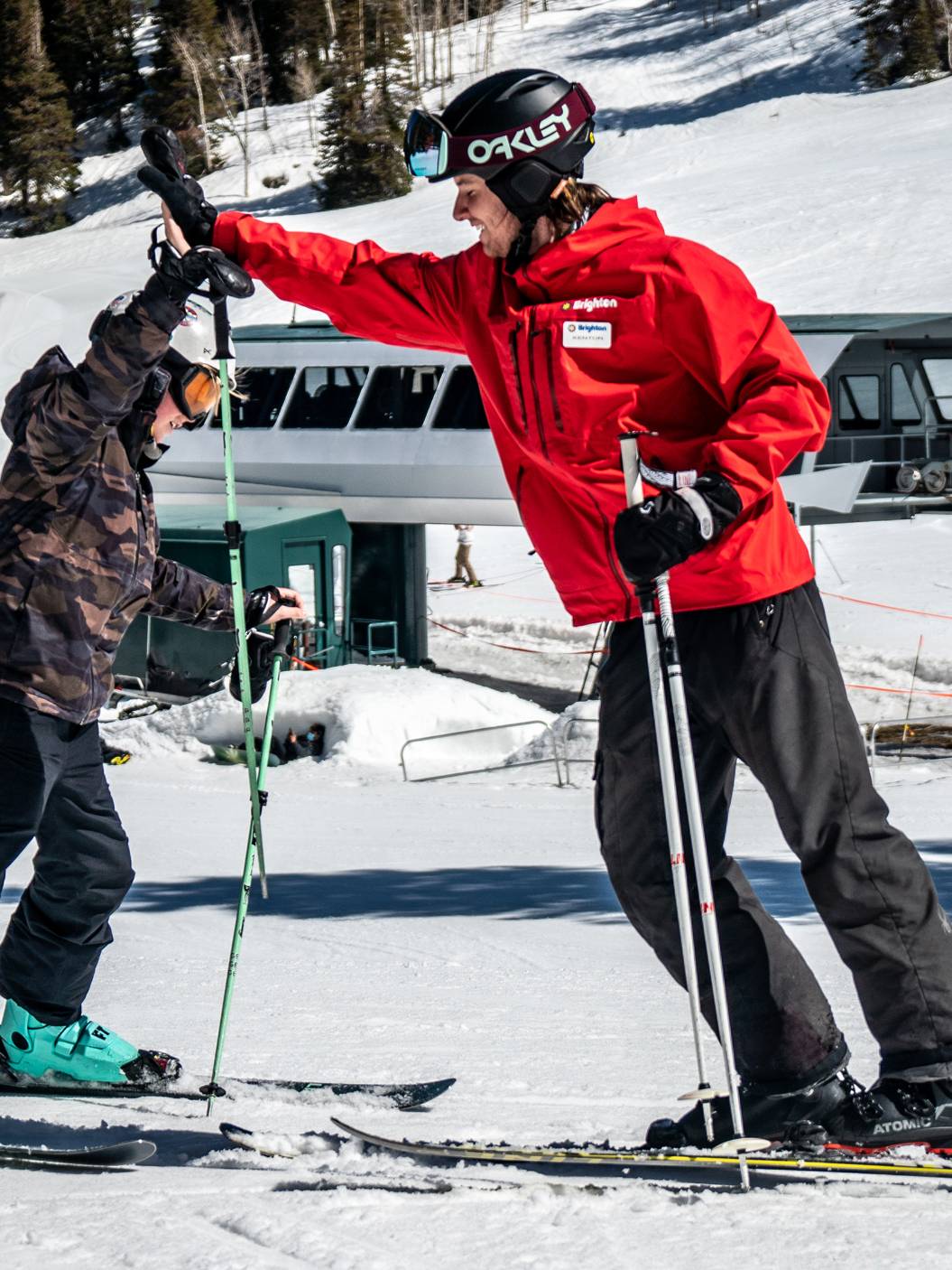 Kid high-fiving instructor during ski lesson