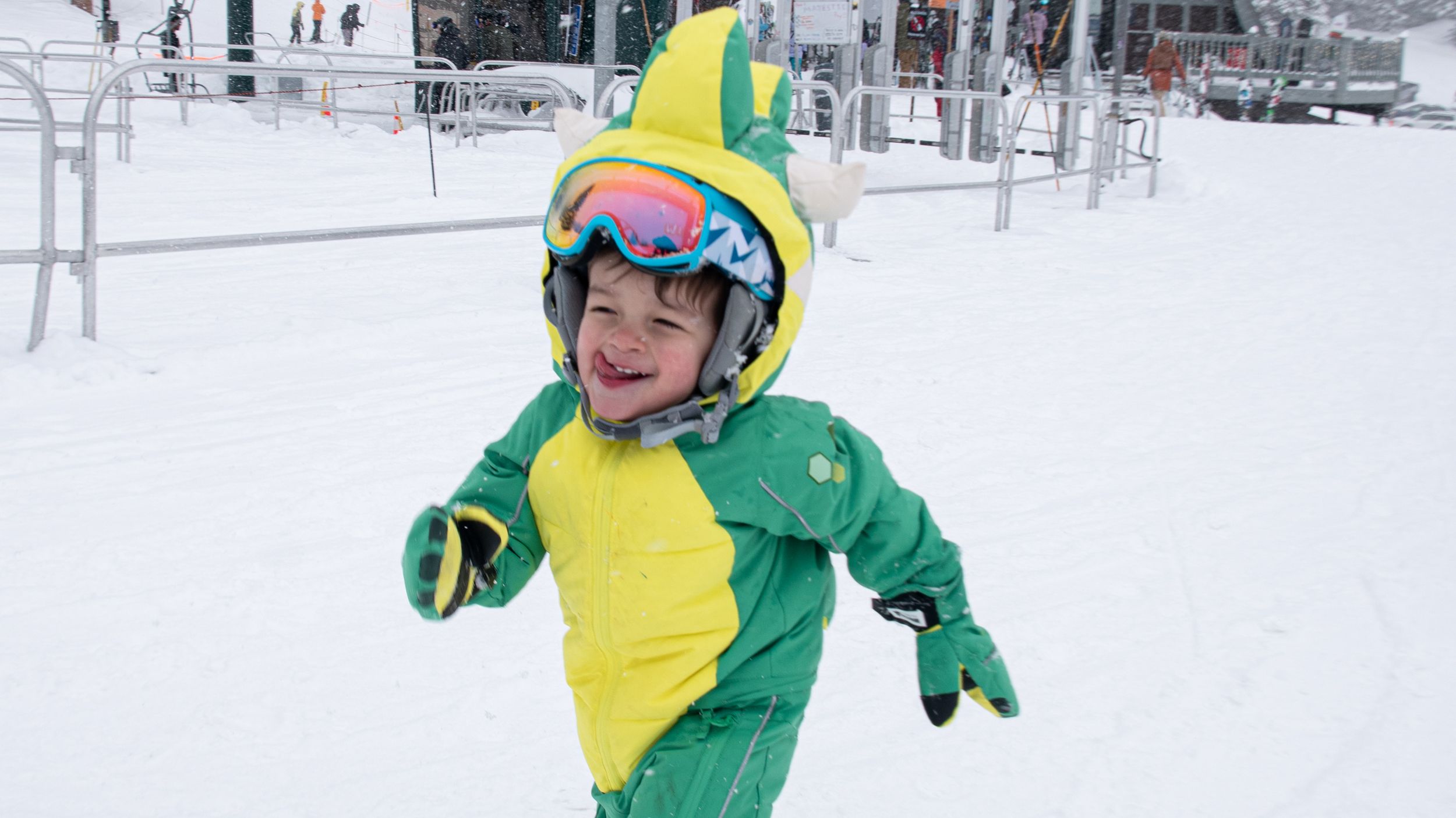 Happy kid in dinosaur ski suit