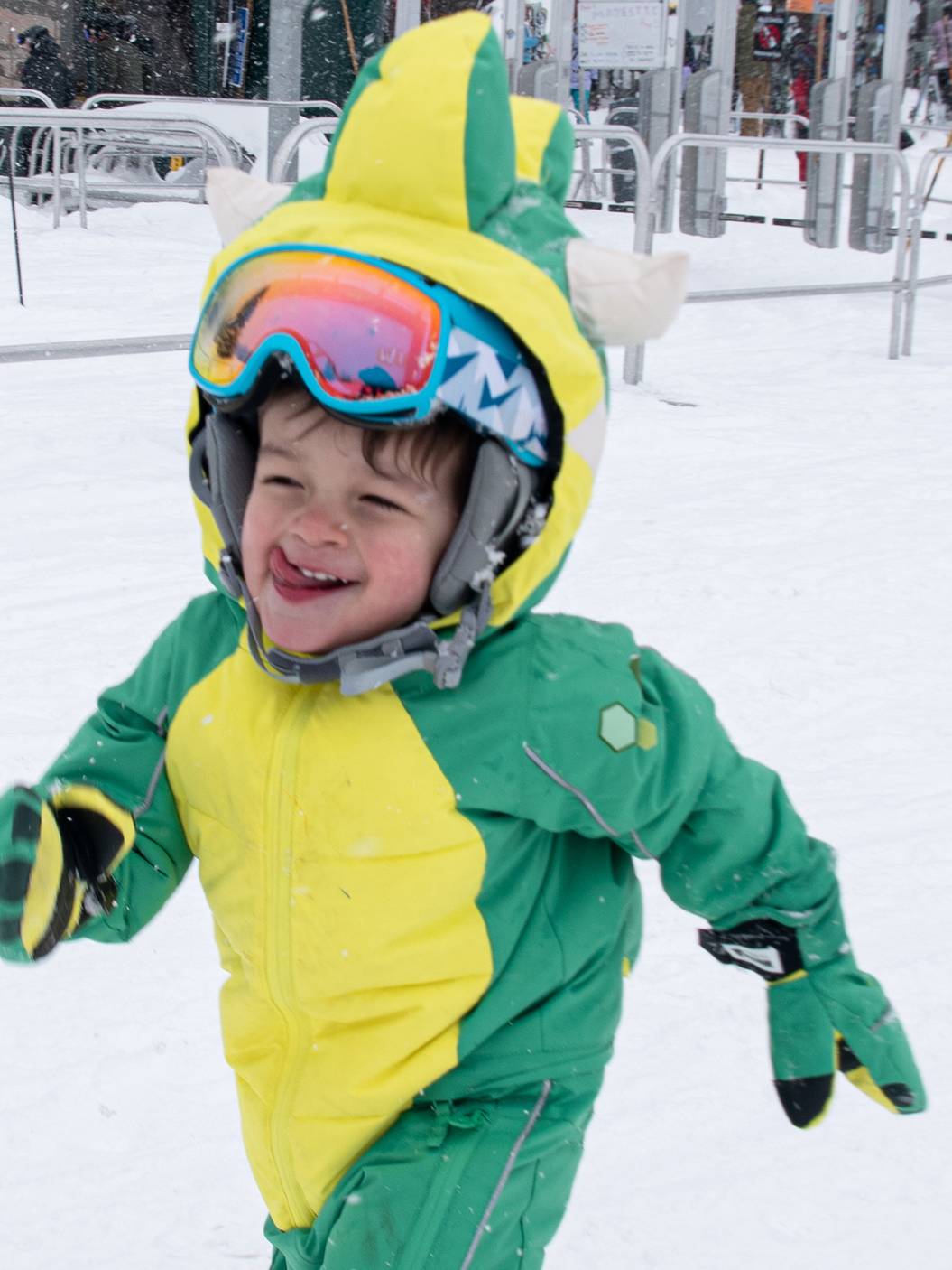 Happy kid in dinosaur ski suit