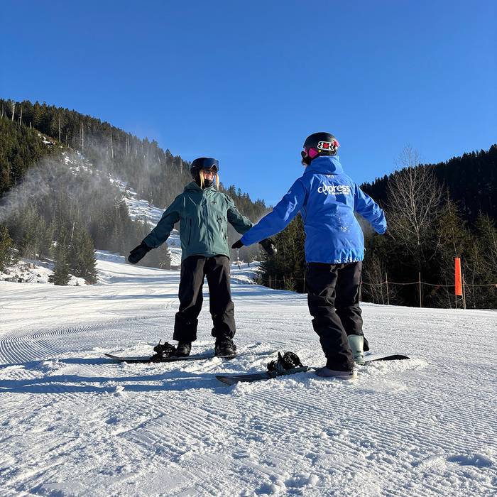 Snowboard instructor teaching a woman on a sunny day.