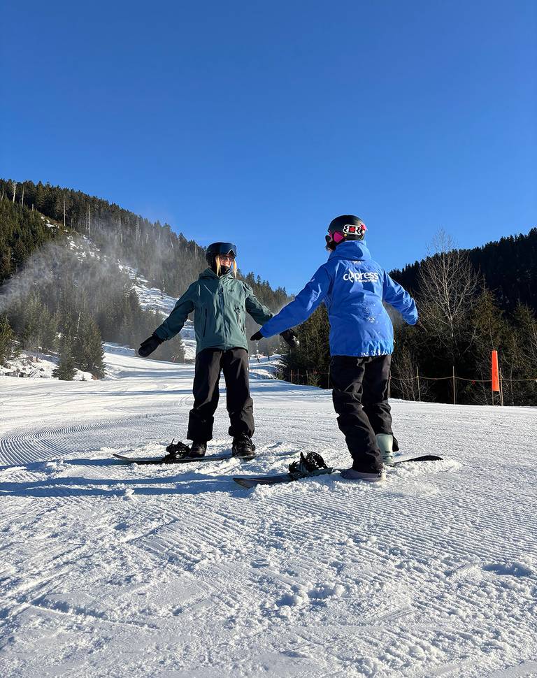 Women skiers and riders in front of a black diamond