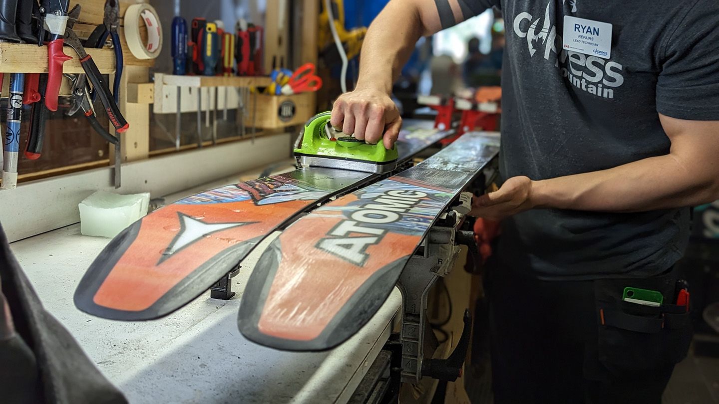 Repair technician waxing skis at the end of season.