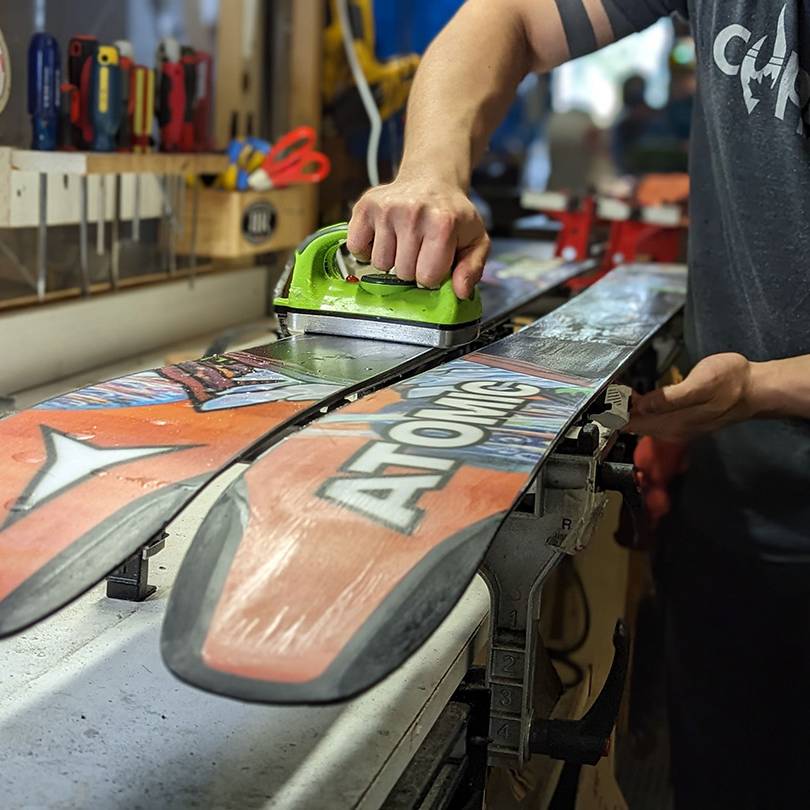 Repair technician waxing skis at the end of season.