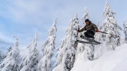 Skier jumping through powder.