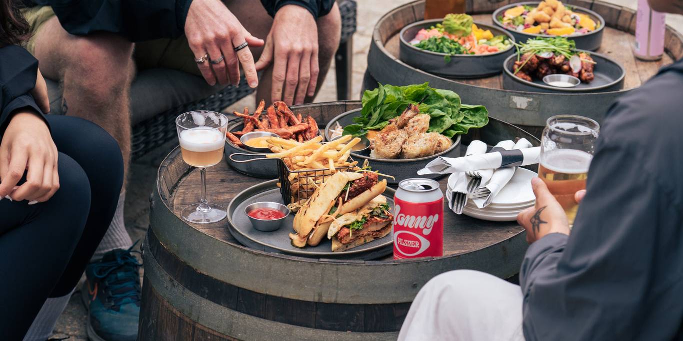 Granville Island umbrellas on a sunny Crazy Raven patio while guests enjoy food and drinks.