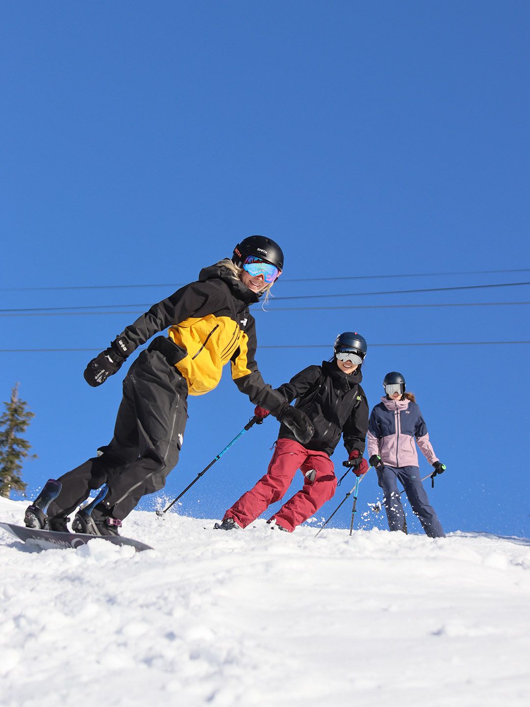 Two skiers and one snowboarder on a bluebird day.