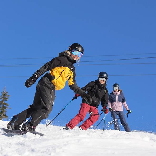 Two skiers and one snowboarder on a bluebird day.