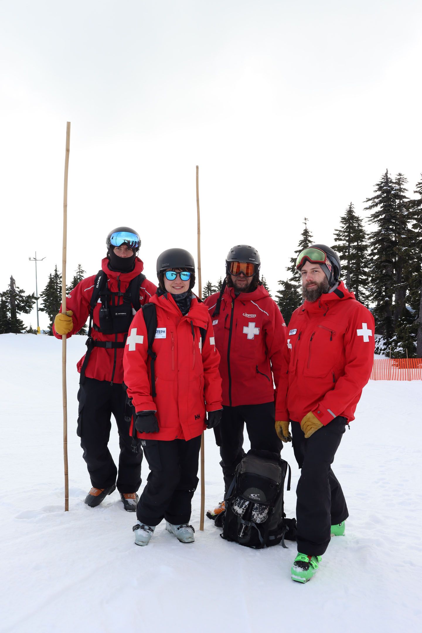 Four patrol staff posing with two of them holding bamboo sticks used for ski boundary.
