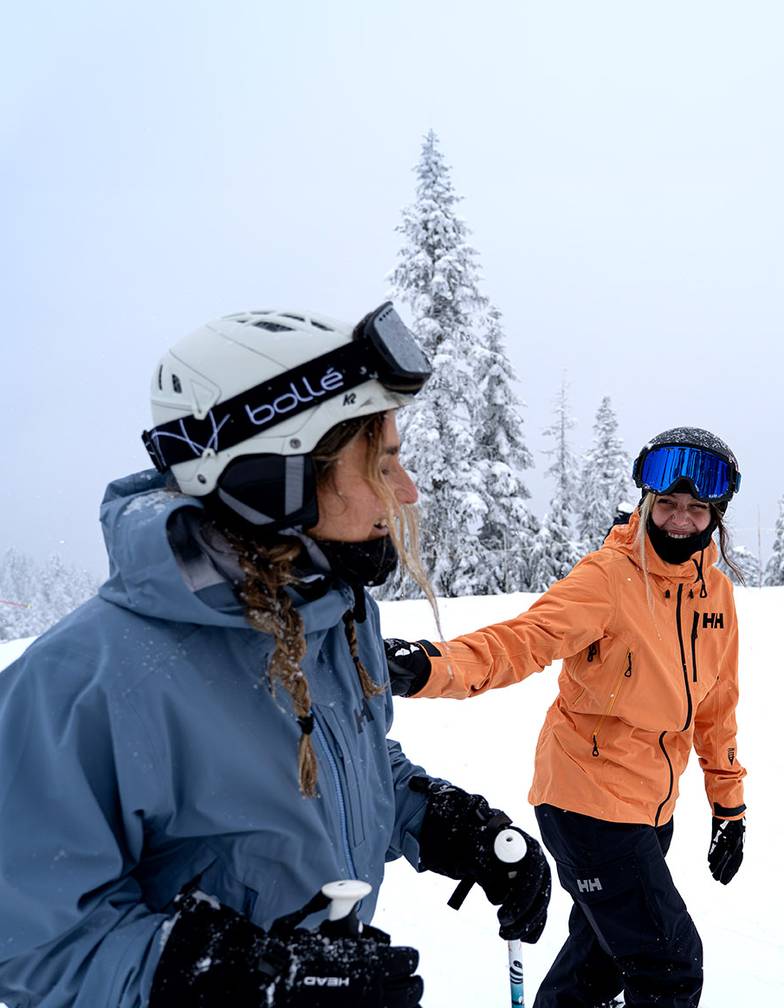 A skier and a snowboarder laughing on snowy hill.