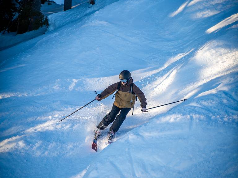 A person skiing downhill on a sunny day.