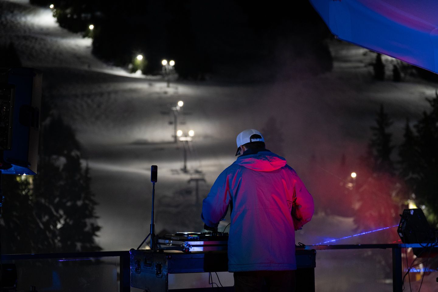 DJ plays music to crowd of people on a Cypress Mountain mountain top patio. 