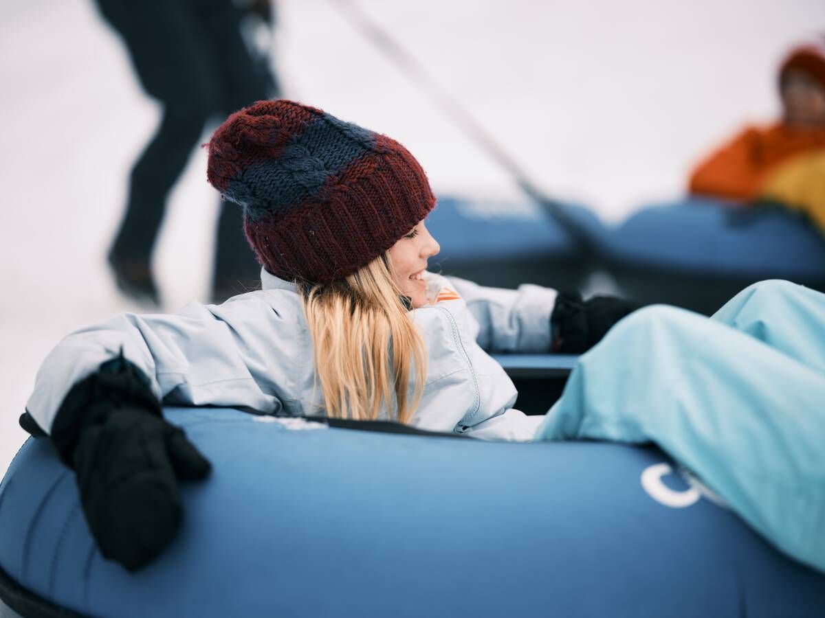 A blonde girl snowtubing.