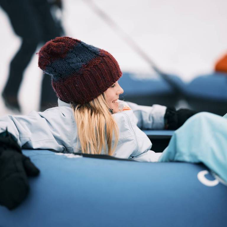 A girl sits in a blue snow tube.