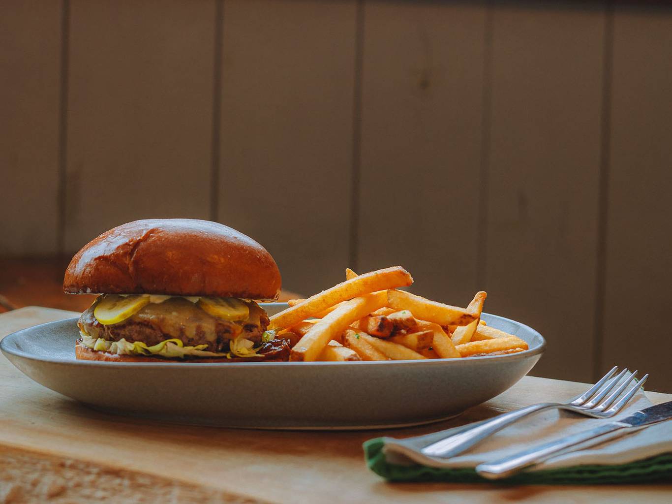 A hamburger and fries on a plate next to a window.