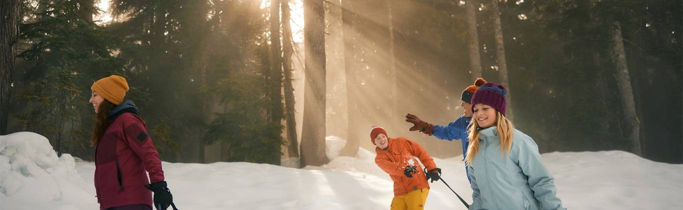 A family dragging snow tubes on snow during sunset.