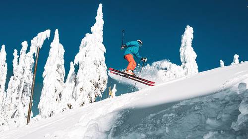 Skier performing a 360 jump from powdery snow.