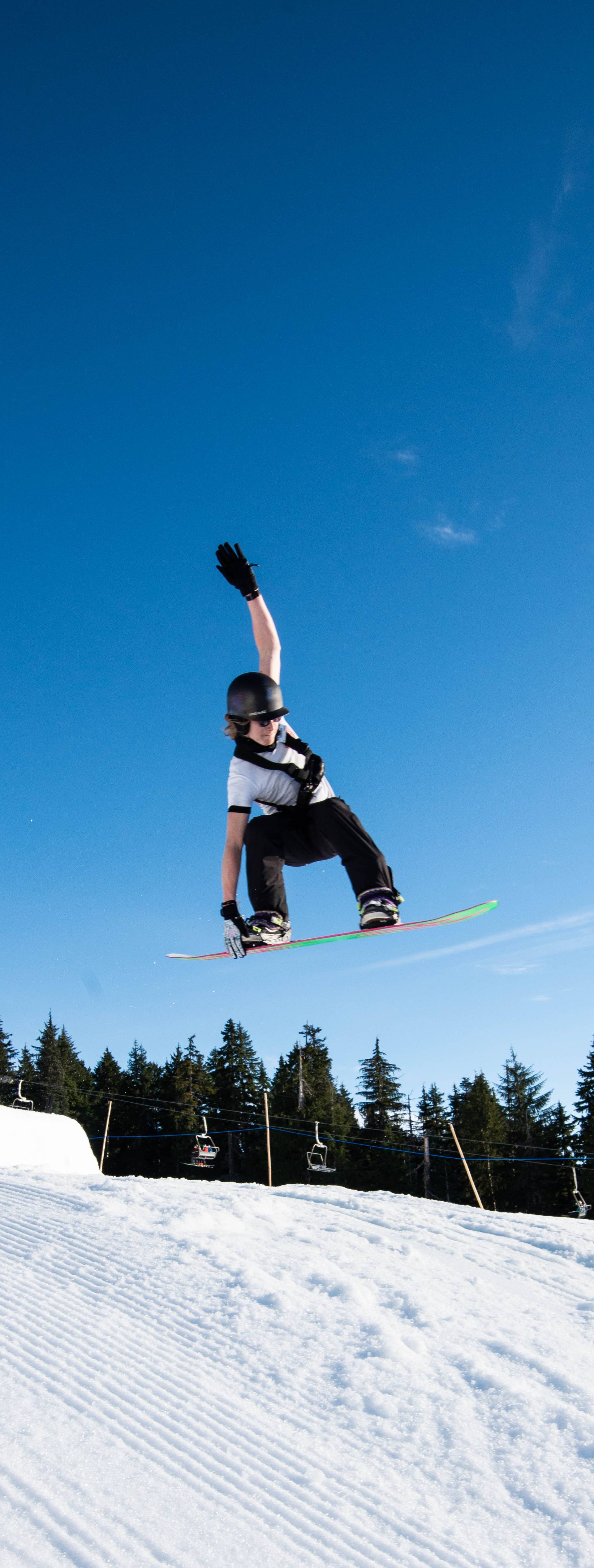 A woman performing a jump on snowboard in Collins Park.