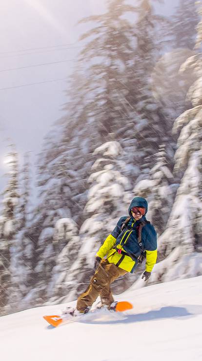 Snowboarder in motion smiling at the camera.