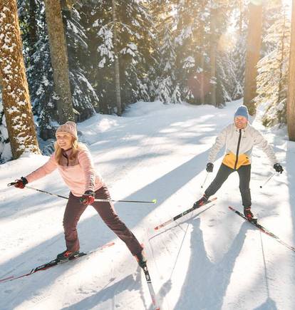A couple cross country skiing on a sunny day.