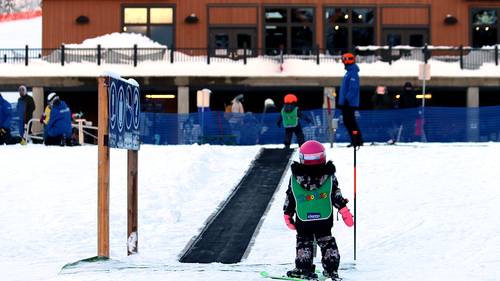 Small child on skis in front of magic carpet.