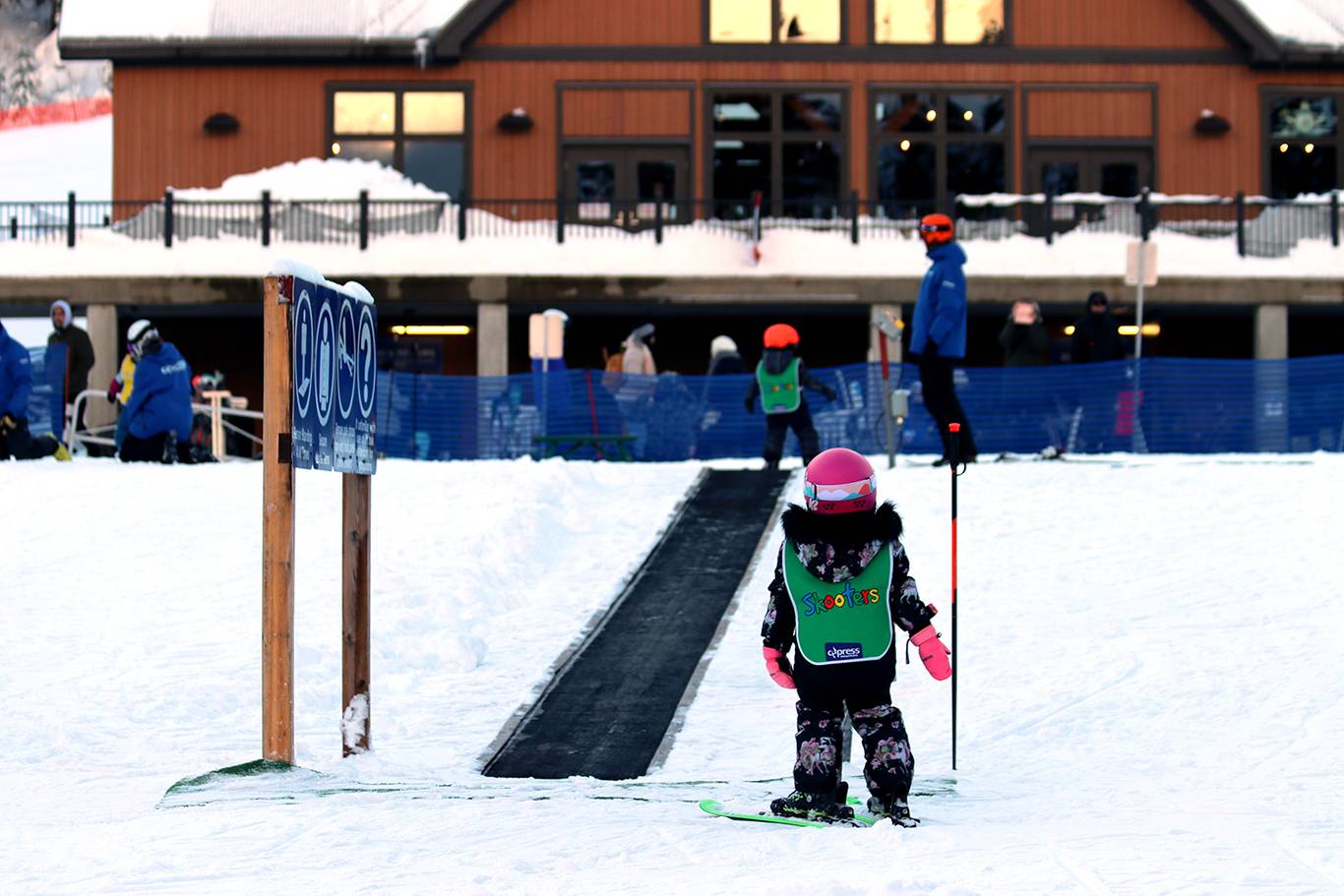 Small child on skis in front of magic carpet.