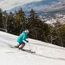 A skier in a blue jacket descends a ski run.