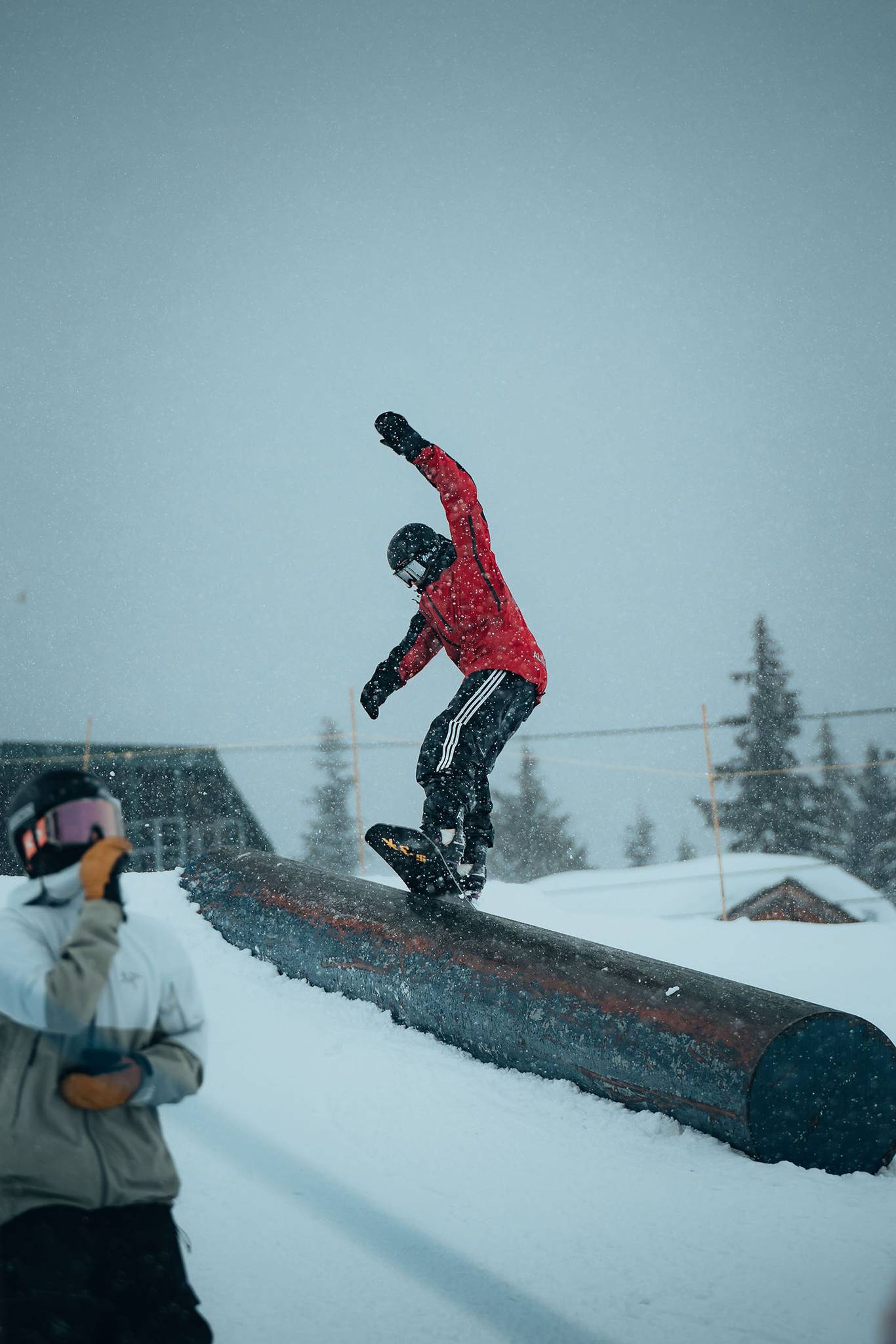 A snowboarder sliding on tube in terrain park.