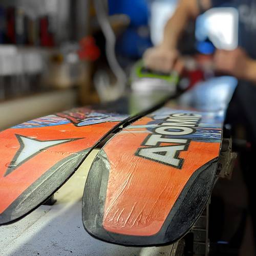 Repair technician waxing a ski.