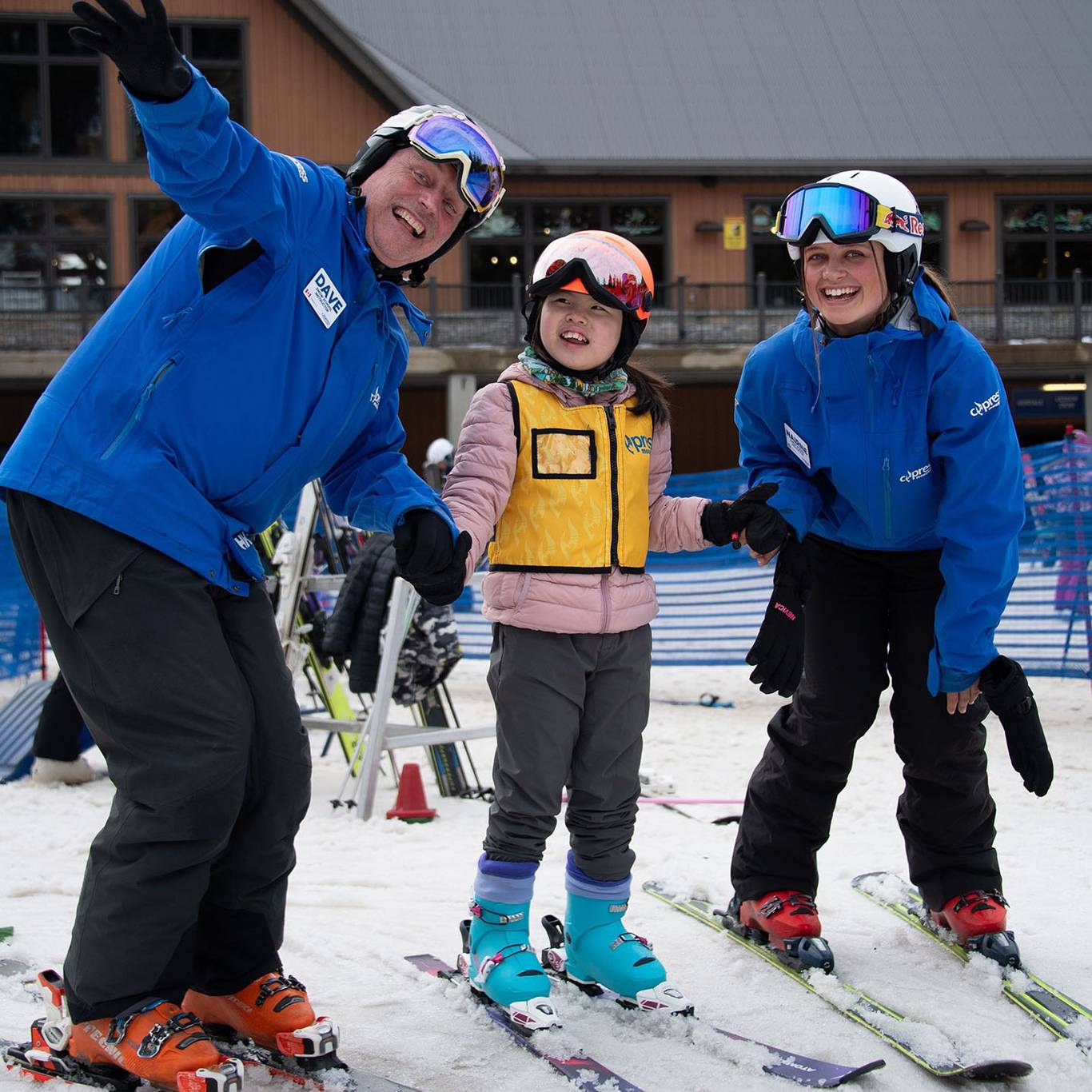 Two instructors posing with a child on skis.