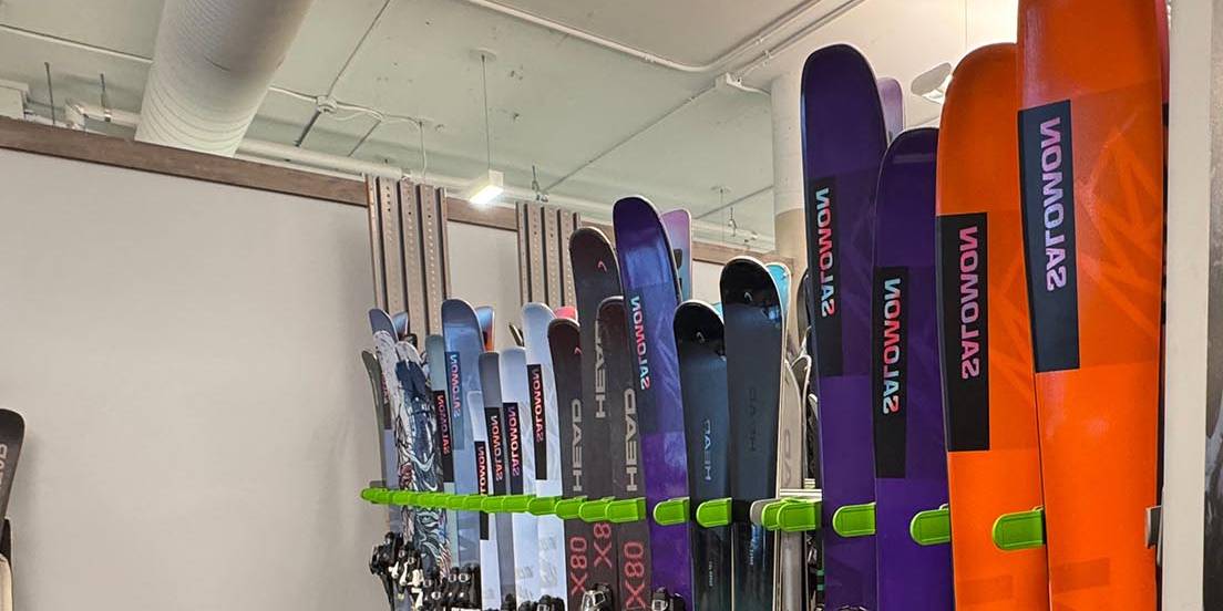 Salomon rental skis lined up in a rental ski shop.
