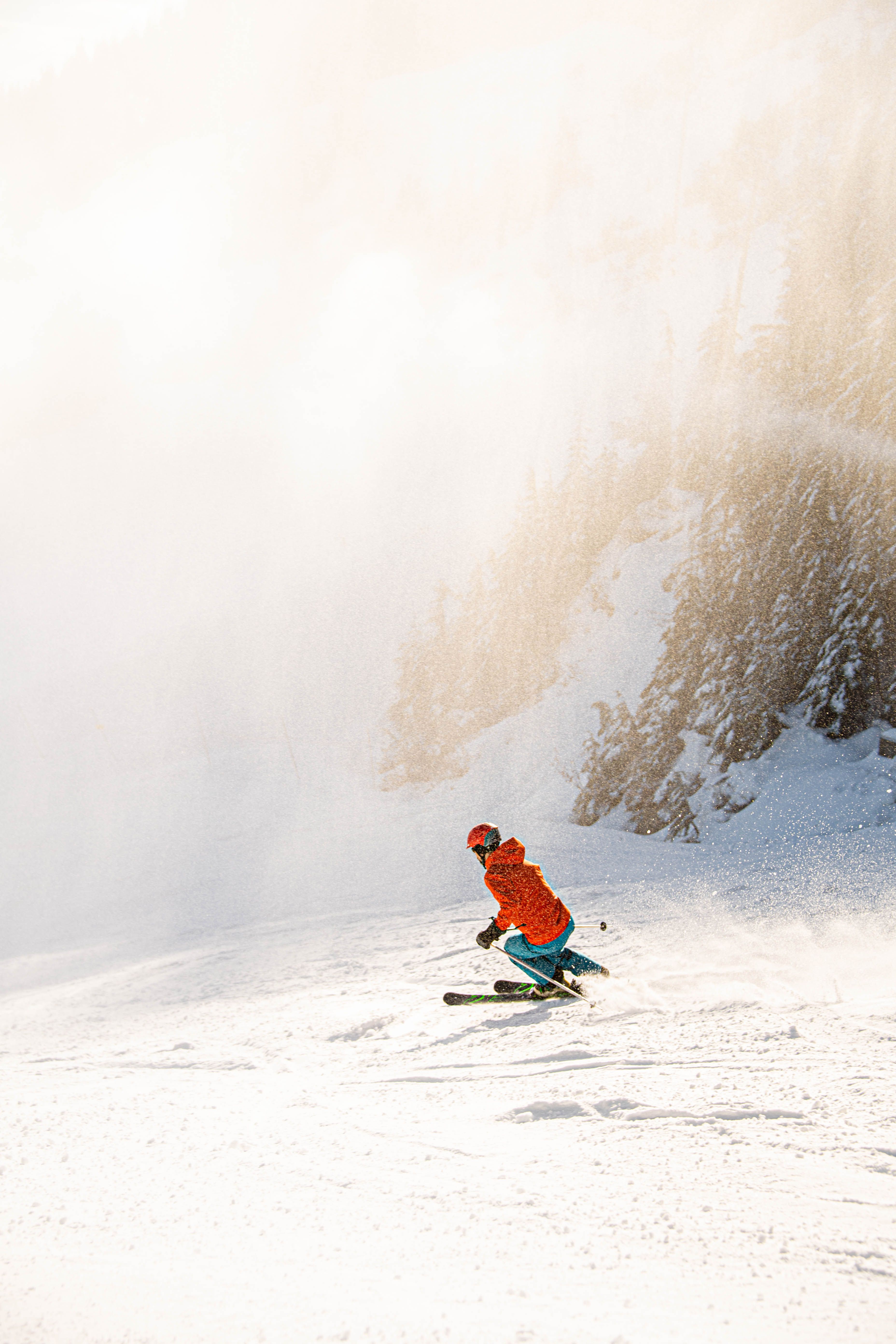A person in red jacket skiing on a foggy and sunny day.