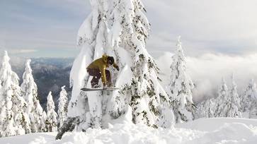 Snowboarder jumping on powdery snow.