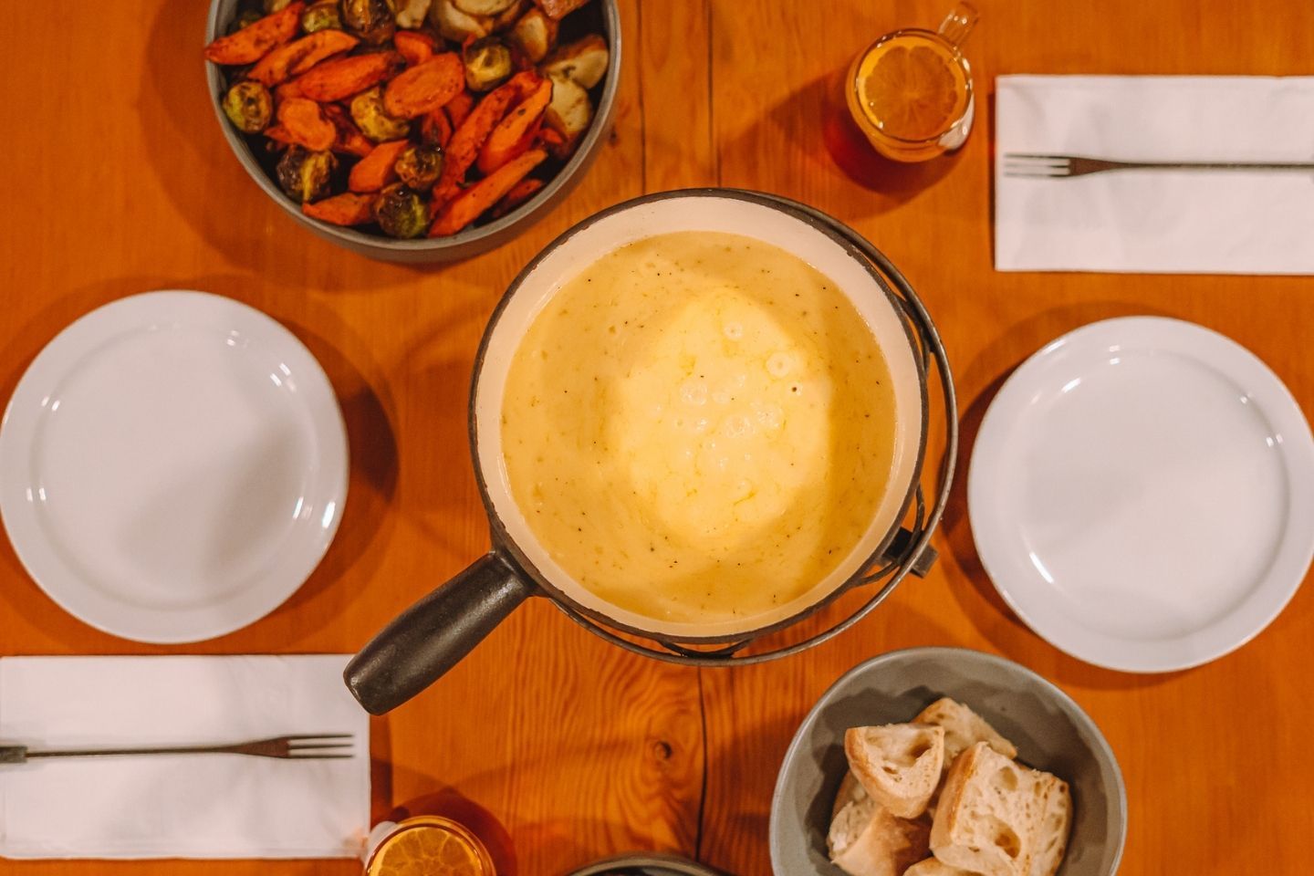 A pot of cheese fondue with bread and mixed vegetables.