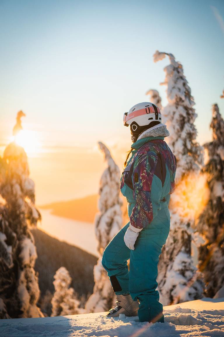 A woman looking at the views through the trees during sunset.
