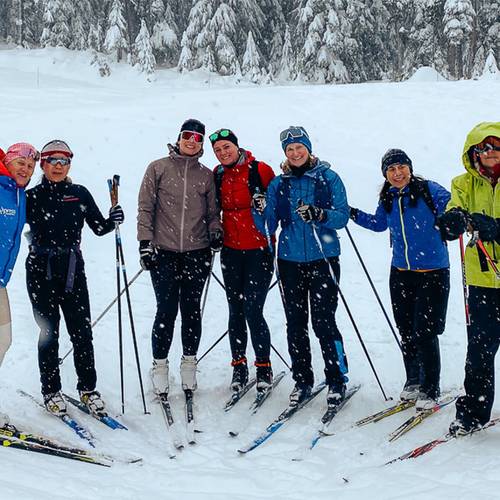 A group of women on cross country skis smile for a photo at Cypress Mountain's Nordic area