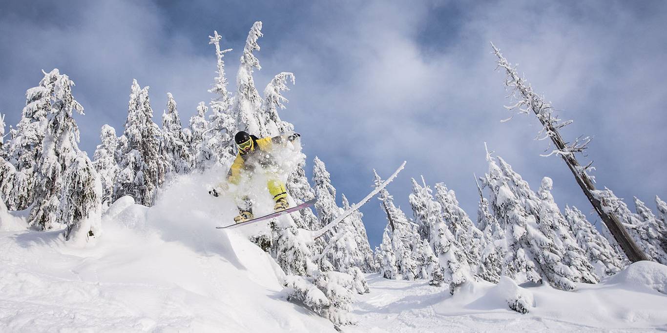 Snowboarder performing a jump on a powder day.