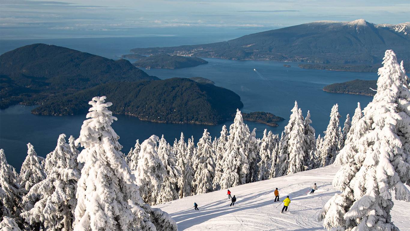View from Sky Chair looking at the ocean with people snowboarding and skiing in the foreground.