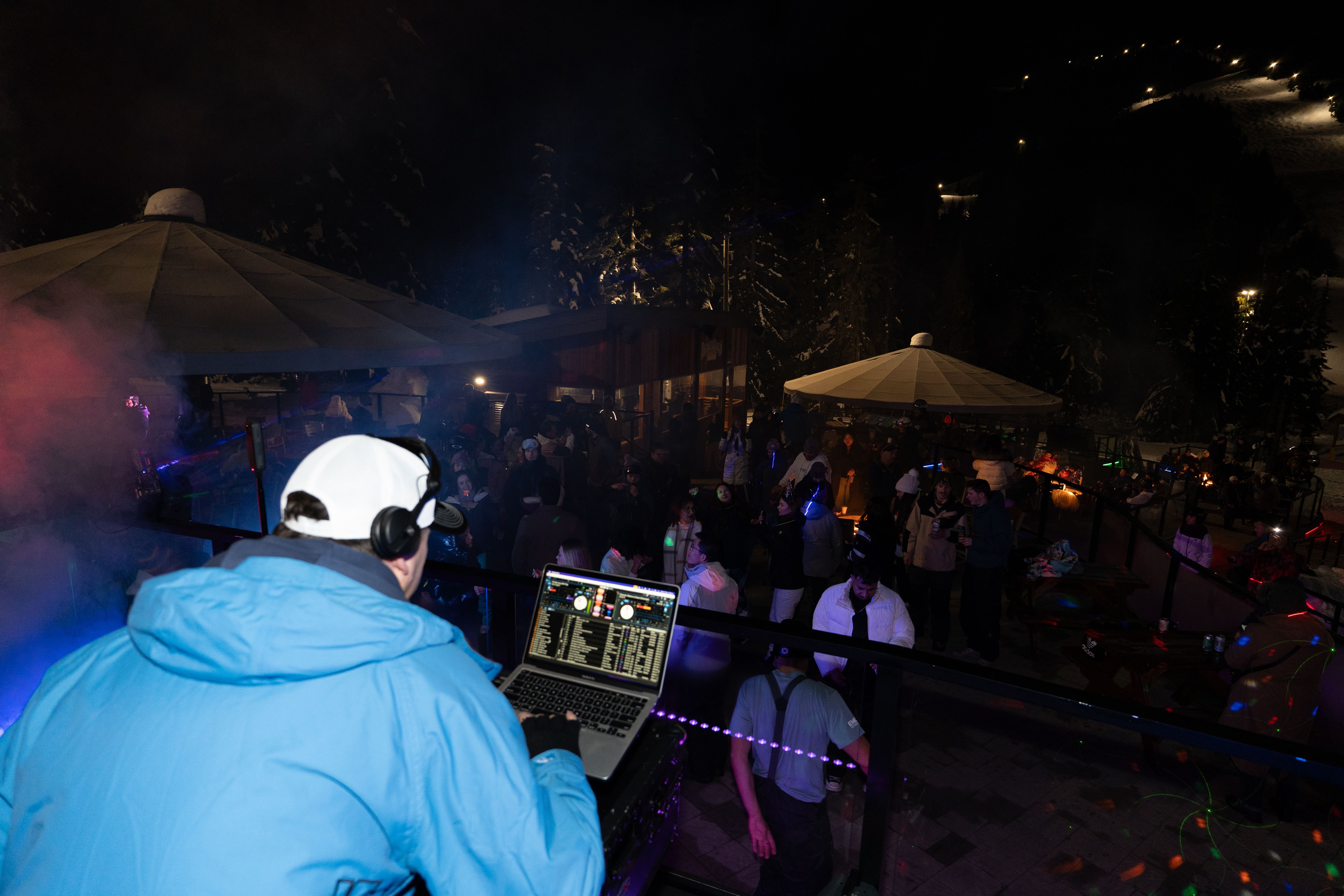 DJ plays music to crowd of people on a Cypress Mountain mountain top patio. 