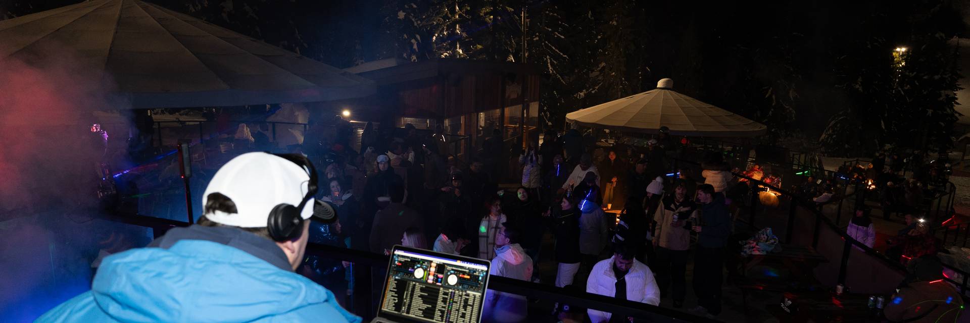 DJ plays music to crowd of people on a Cypress Mountain mountain top patio.