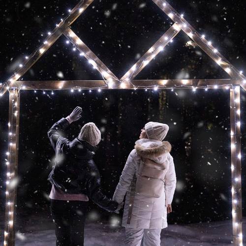 A couple snowshoes to Cypress Mountain's Hollyburn Lodge surrounded by twinkling lights and falling snow