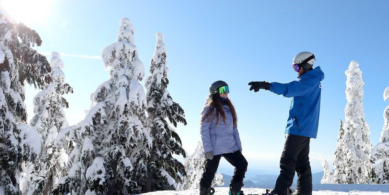 Snowboard instructor teaching a student how to ski a green run on Cypress Mountain resort.