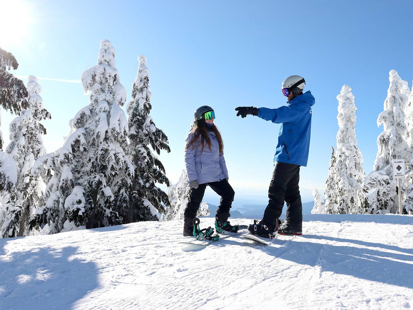 Snowboard instructor pointing and talking to an adult student.